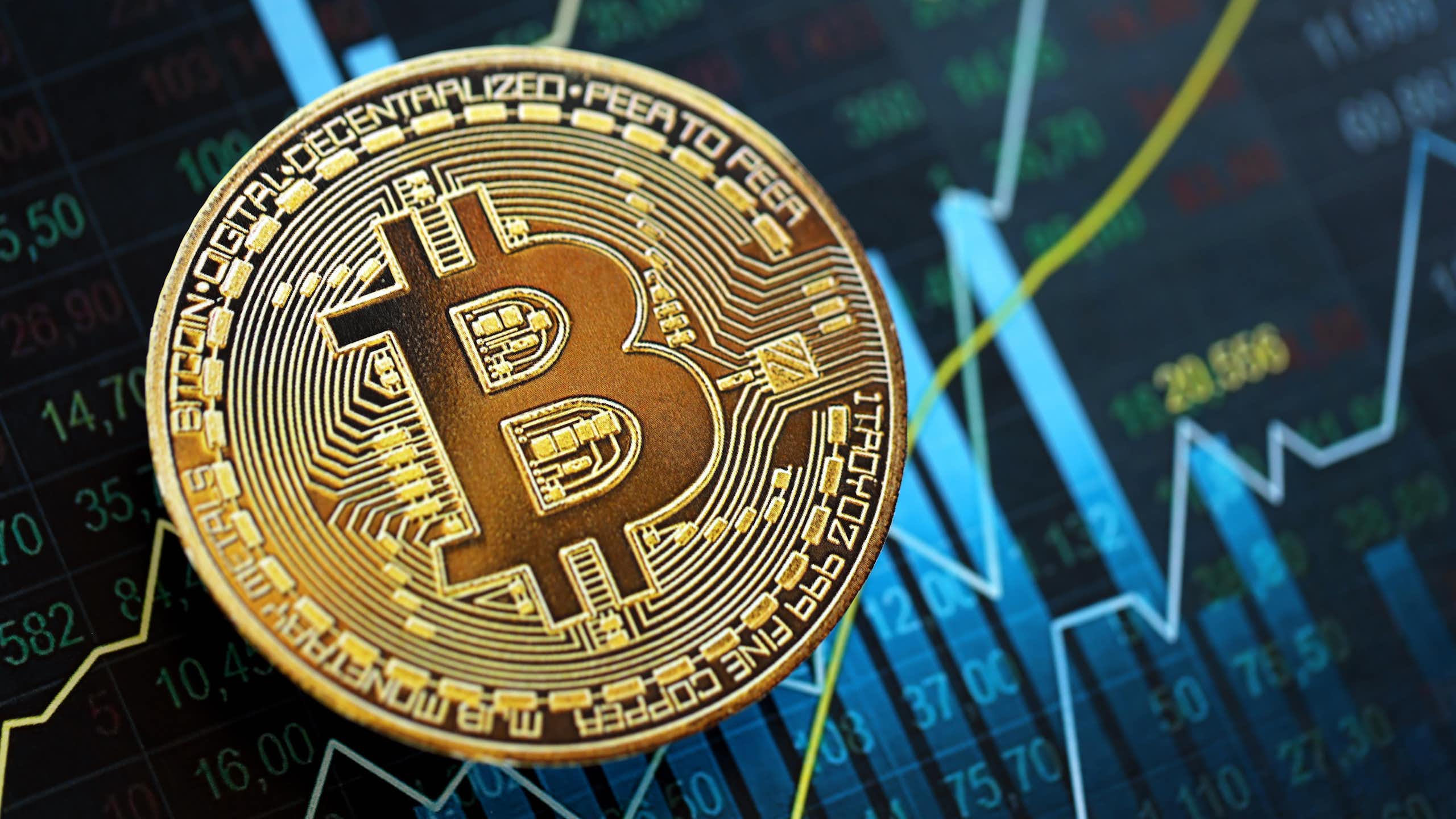 The bitcoin symbol on a background with charts