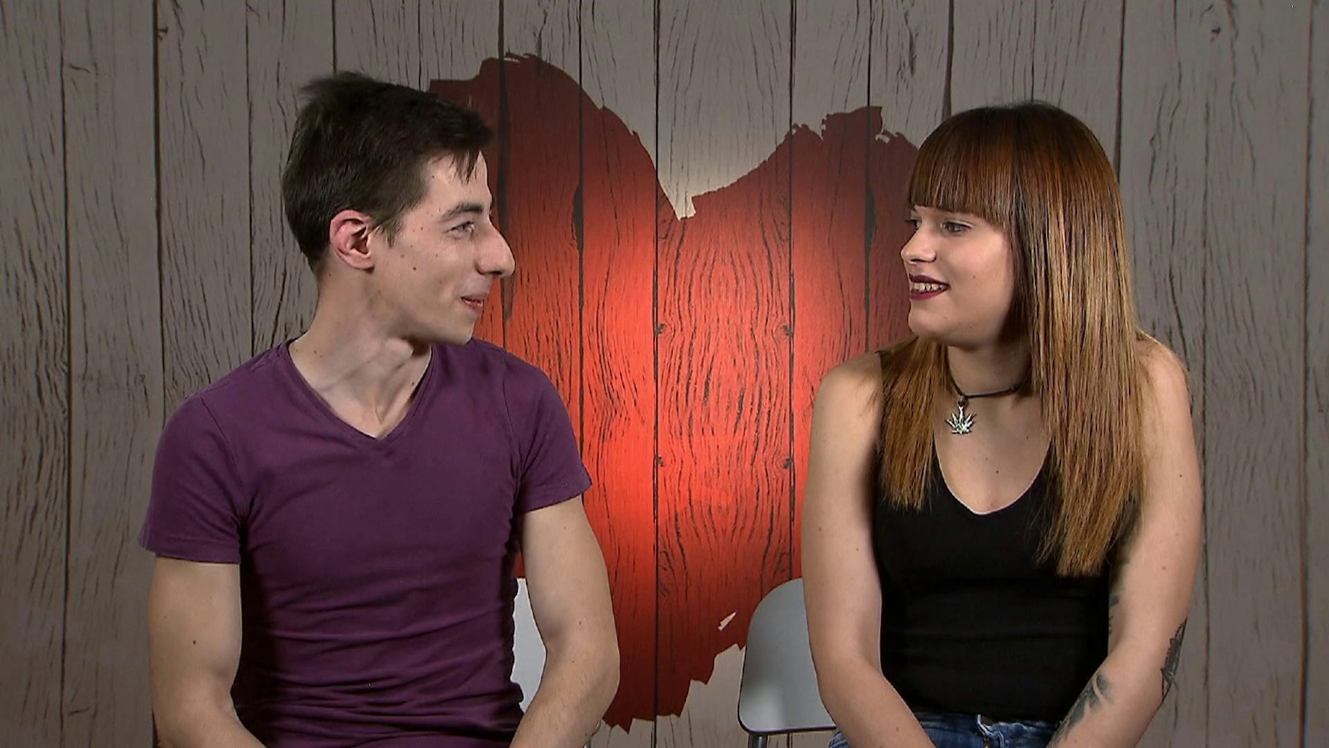 Dos jóvenes mirándose a los ojos con la imagen de un corazón al fondo.