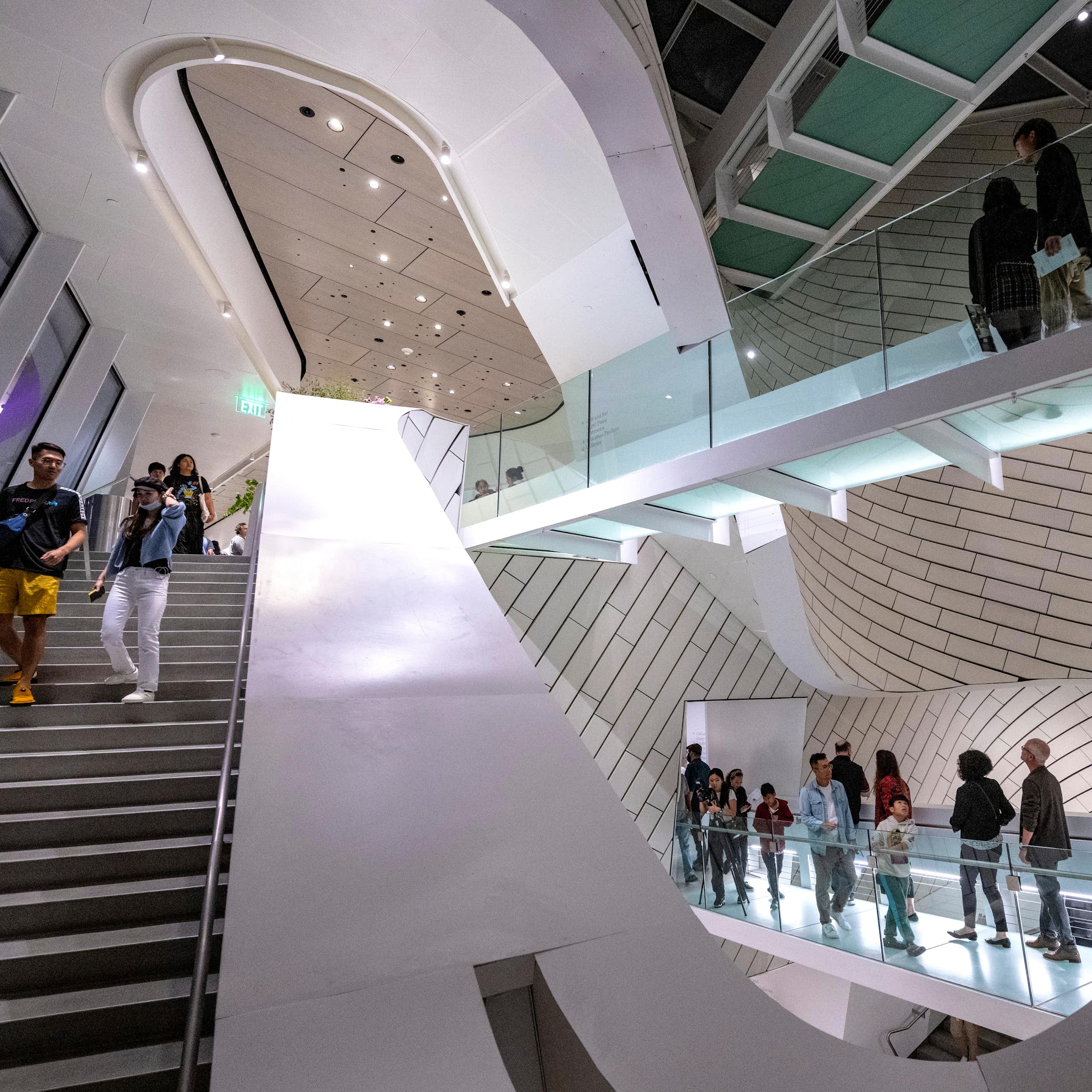 People mill around a very modern and artistic-looking stairwell and catwalk.
