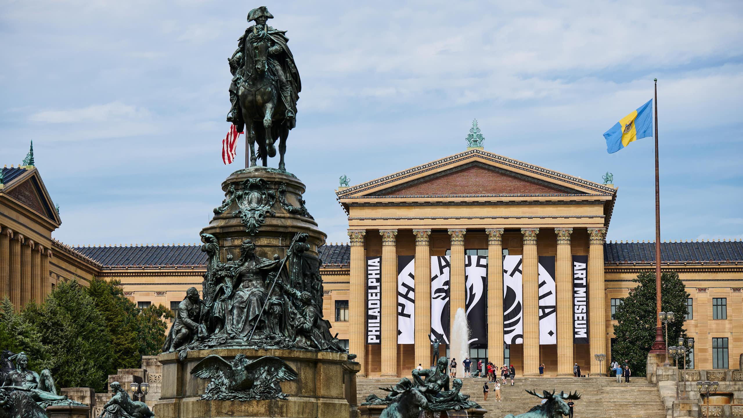 Statues in front of ornate Greek Revival-style building with sign that says 'Philadelphia Art Museum'