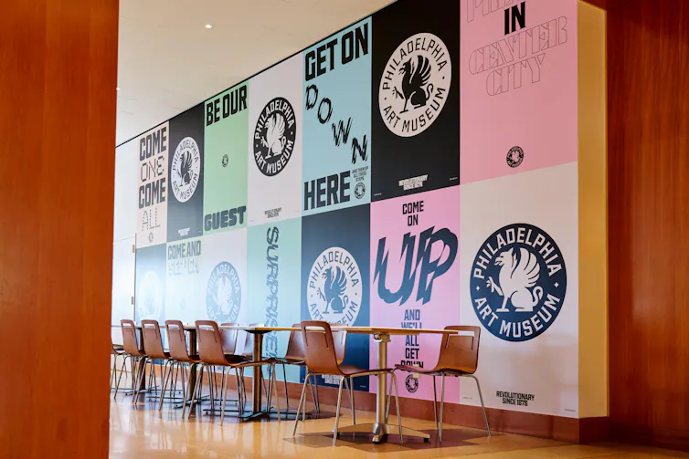 A wall with colorful white, pink, blue, teal and black signs with modern graphic designs