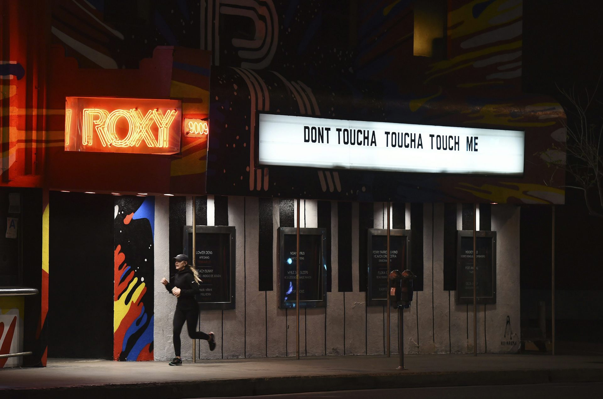 Una persona pasa corriendo junto a una tienda de campaña en la oscuridad que dice 