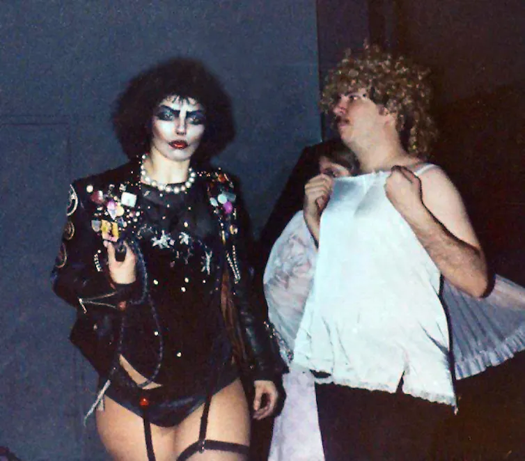 One person dressed in fishnet stockings, a bustier and heavy makeup and another in a large blond wig.