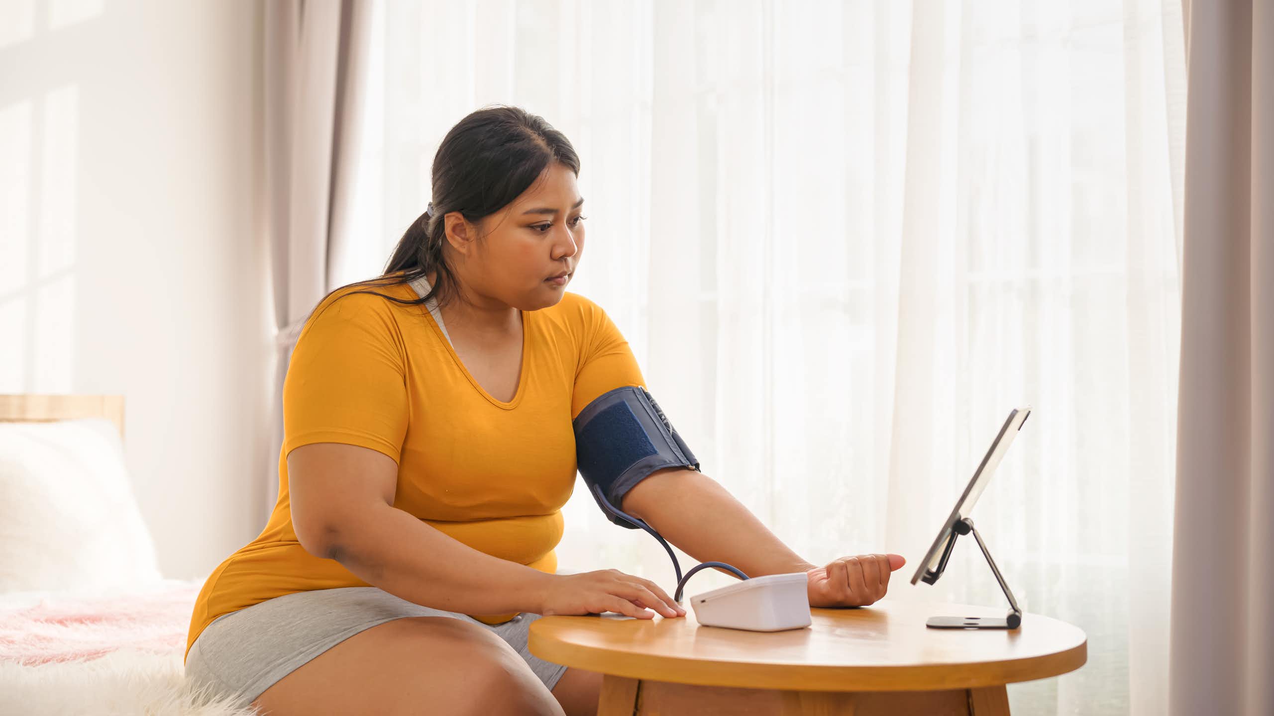 Woman taking her blood pressure while on a video call with doctor
