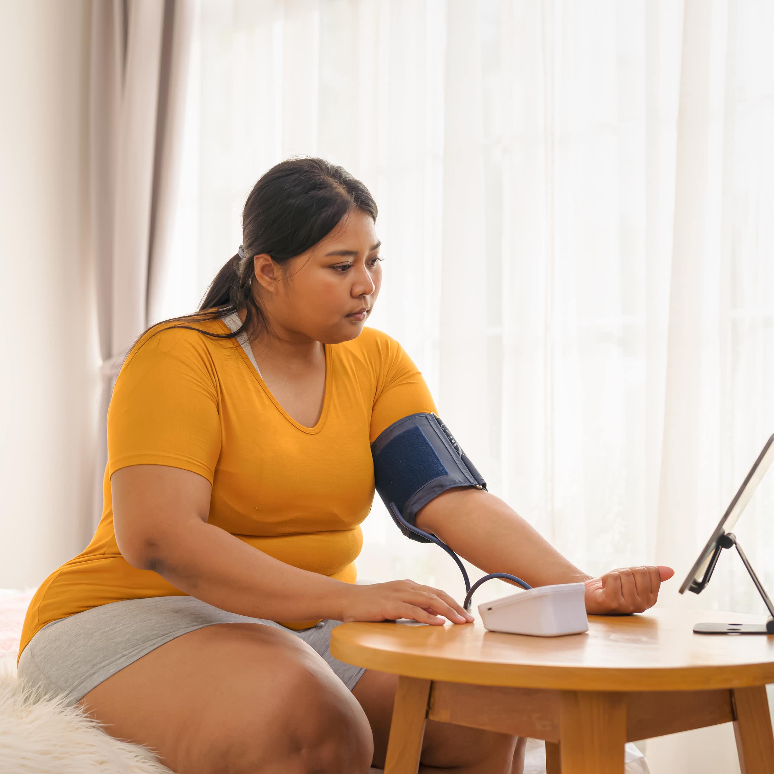 Woman taking her blood pressure while on a video call with doctor