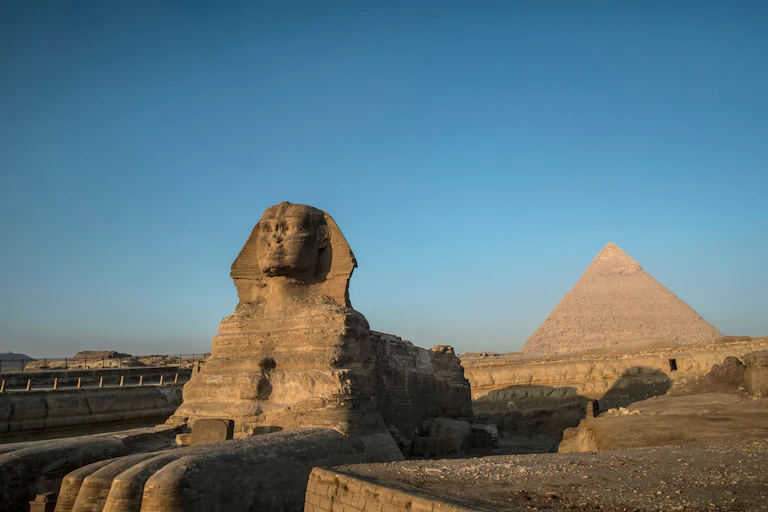 The Sphinx lies next to a pyramid in Egypt.