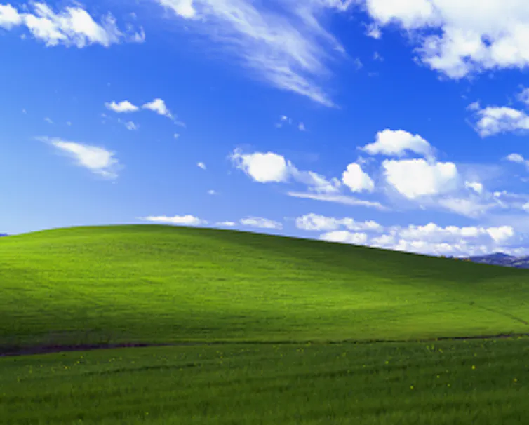 A colorful stock photo of green rolling hills, a blue sky and clouds.