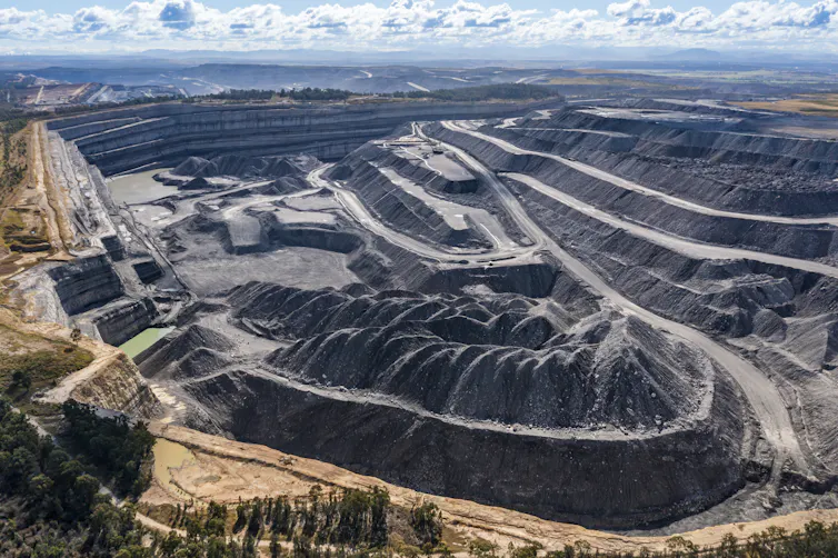 open-cut coal mine seen from above, paths left by trucks and deep hole.