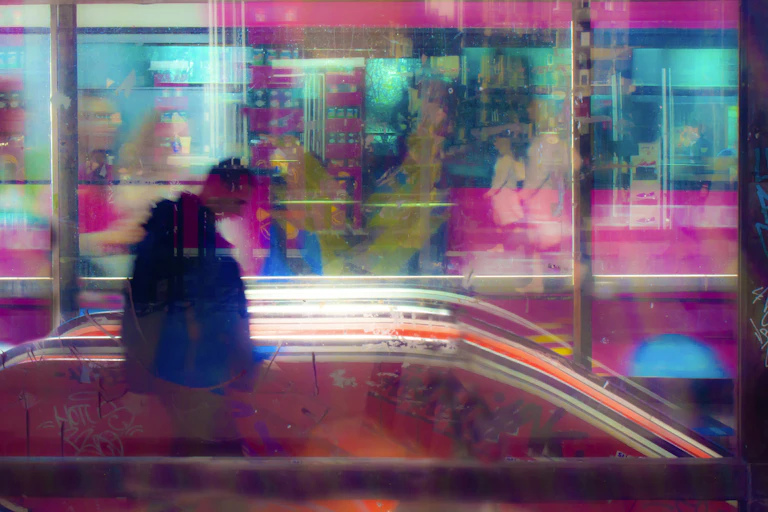 Blurry colourful city scene with man heading down an escalator.