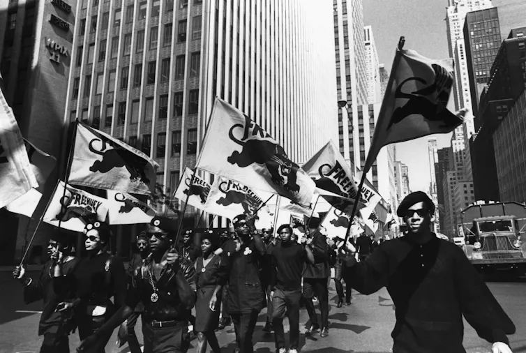 African American protesers in matching outfits march on the street.