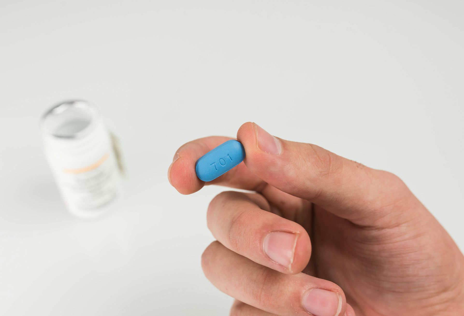 A person holds a blue Prep pill in their hand.
