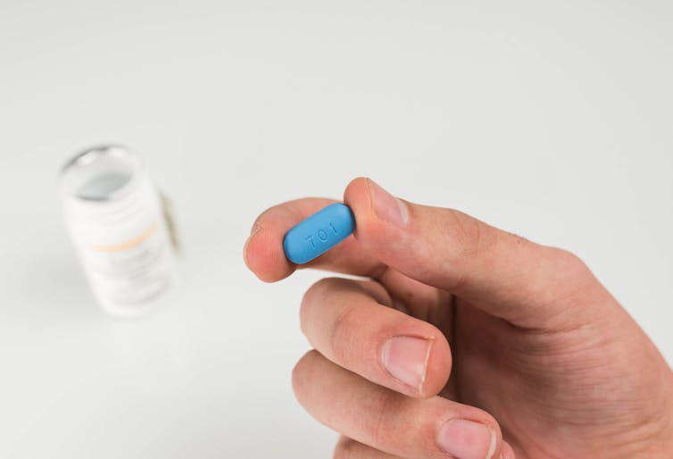 A person holds a blue Prep pill in their hand.
