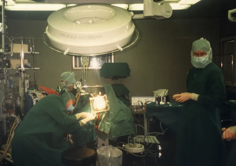 Doctors and nurses wearing gowns and masks prepare a patient for surgery.