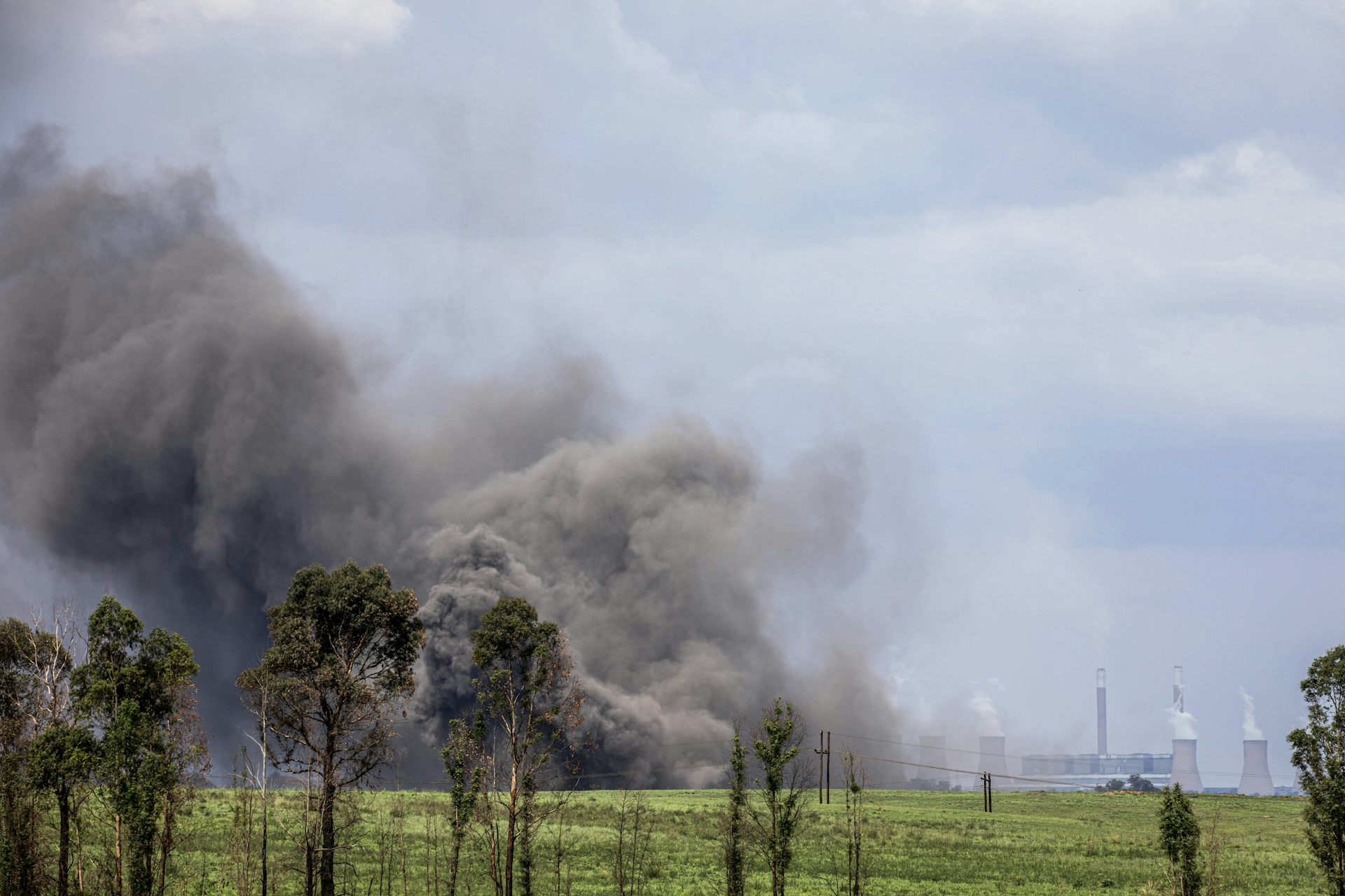 Huge grey cloud of dust rises into the air; in the distance are power station cooling towers