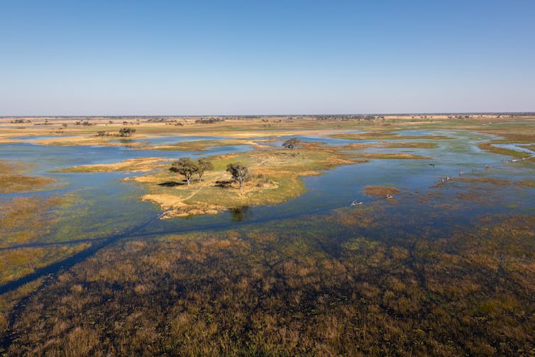 An aerial photo of a vast land of water and rocky. Small boats cross the water.