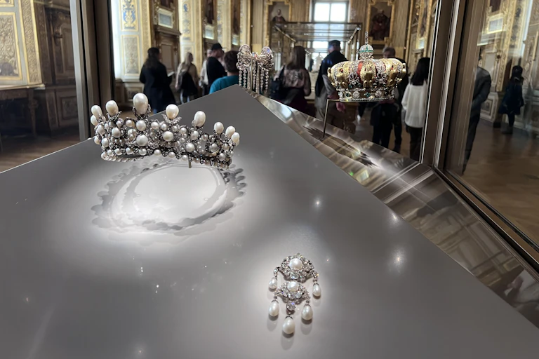 Museum display featuring a silver tiara and a crown.