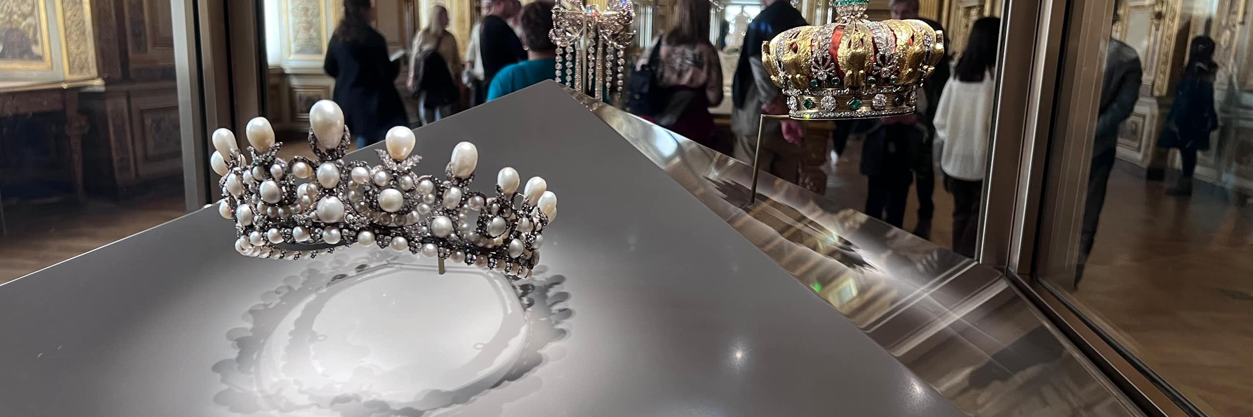 Museum display featuring a silver tiara and a crown.