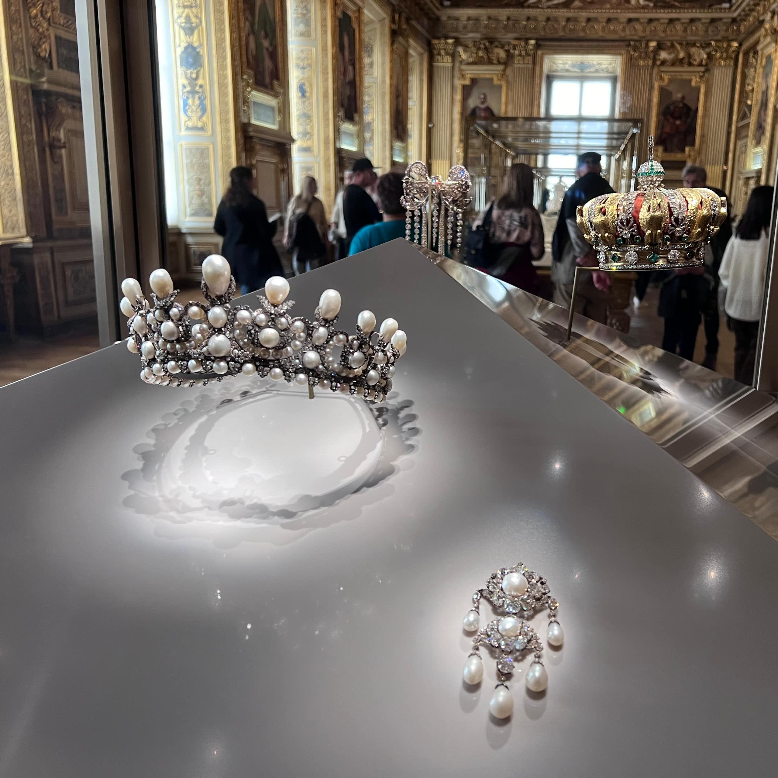 Museum display featuring a silver tiara and a crown.