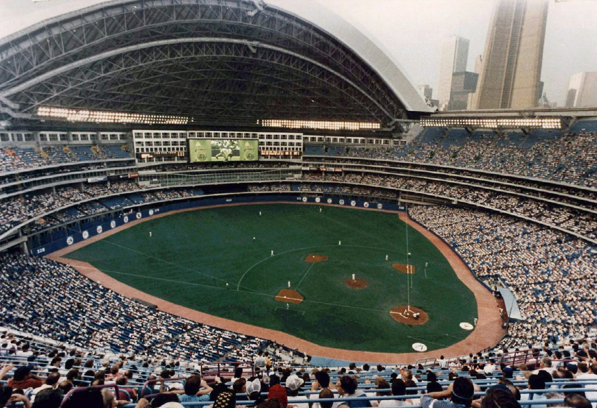 Un estadio de béisbol con techo retráctil abierto lleno de aficionados.