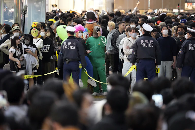 Police officers control the crowd gathering for Halloween celebrations in Japan.