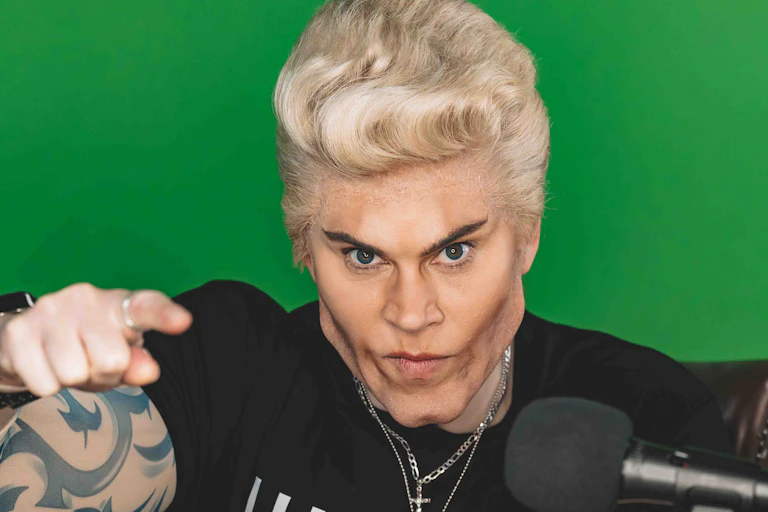 A woman dressed up as a man who has had too much plastic surgery.