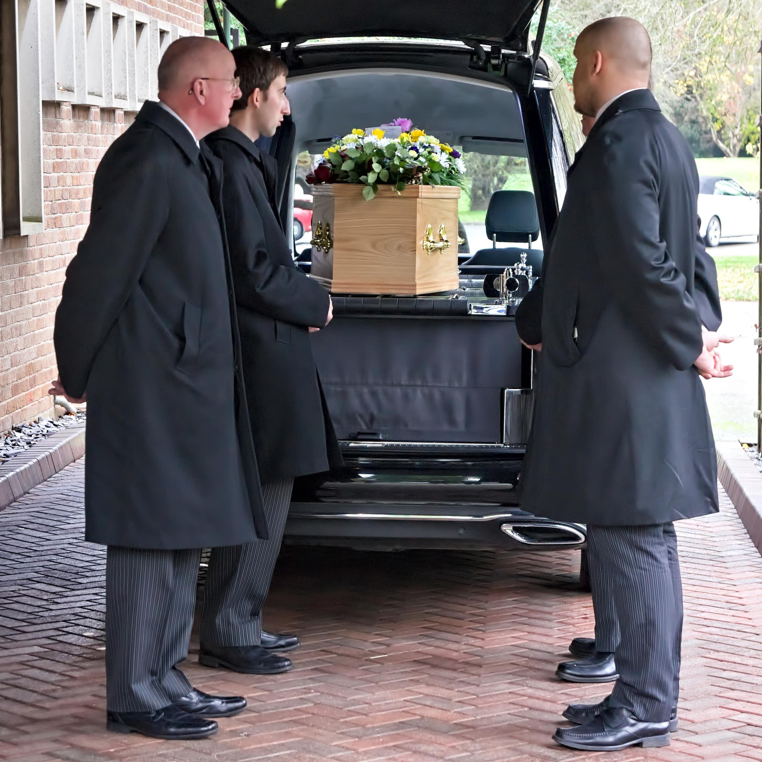 Employés de pompes funèbres devant un cercueil