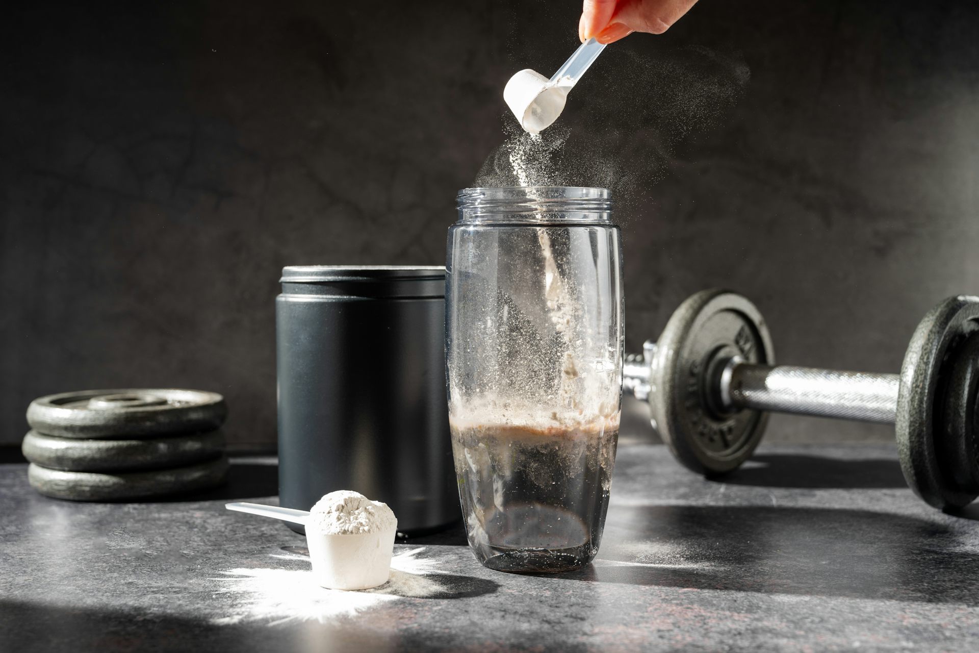 A person dumps a scoop of creatine powder into a cup.