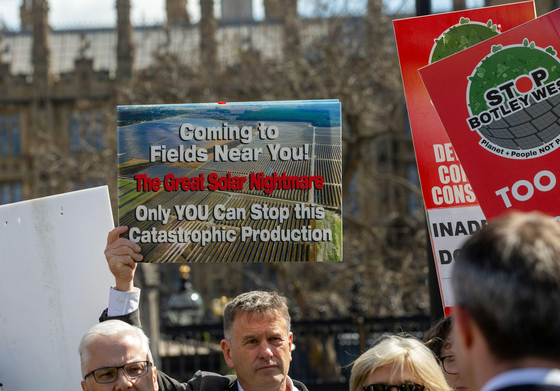man at protest holds anti-solar farm sign