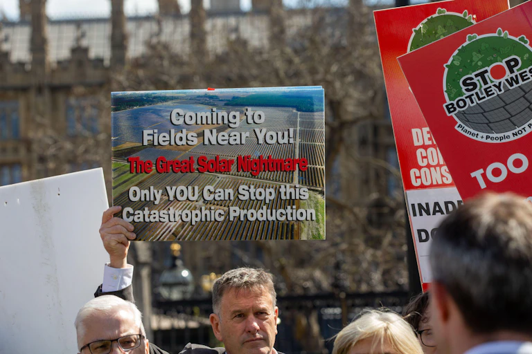 man at protest holds anti-solar farm sign