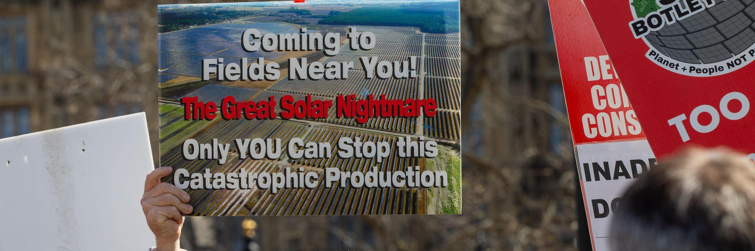 man at protest holds anti-solar farm sign