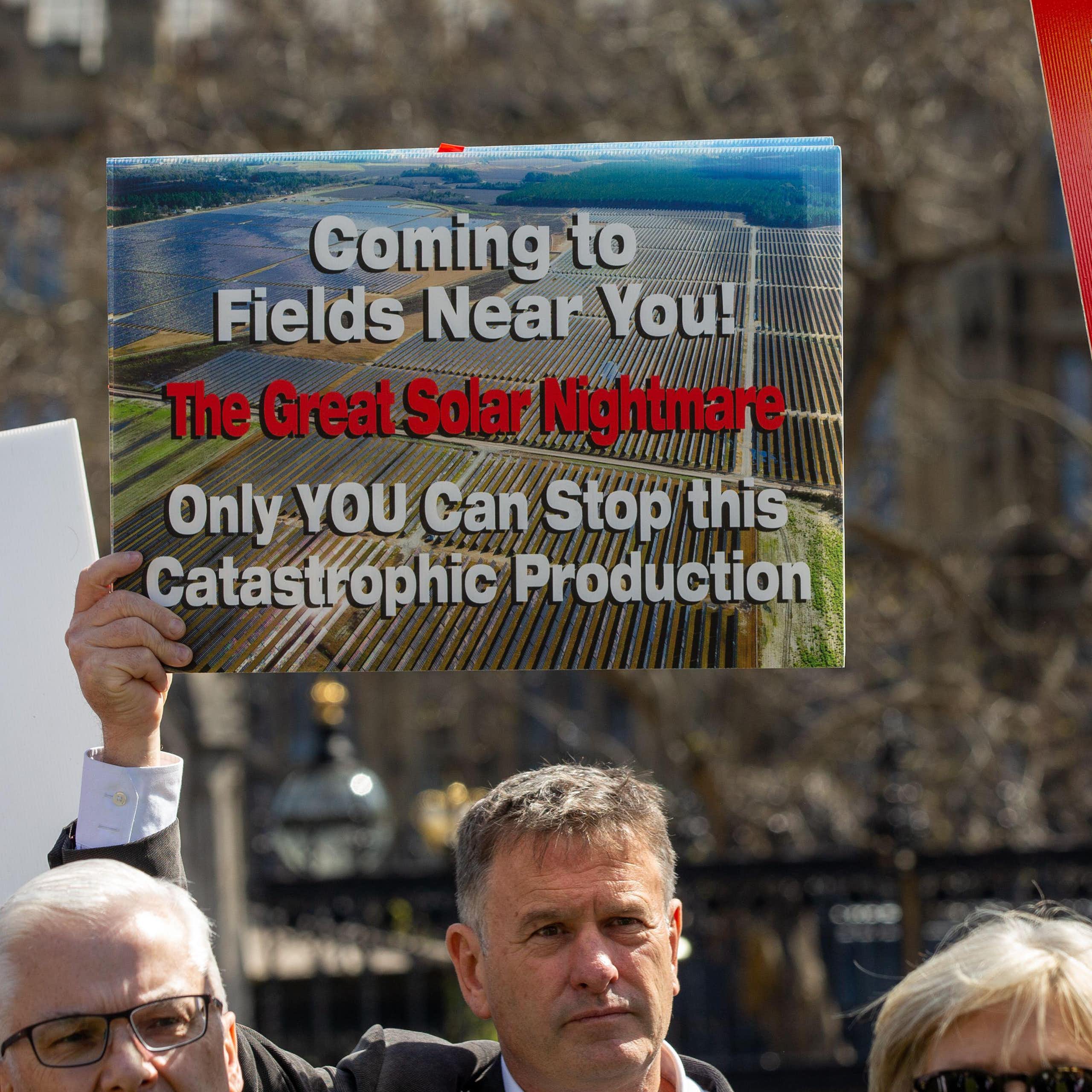 man at protest holds anti-solar farm sign