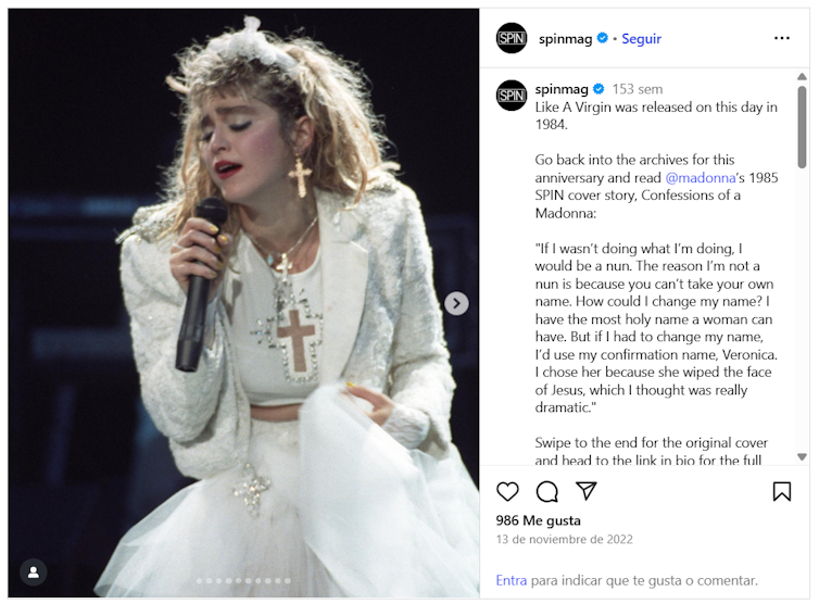 Una mujer rubia vestida de blanco canta con un crucifijo al cuello.