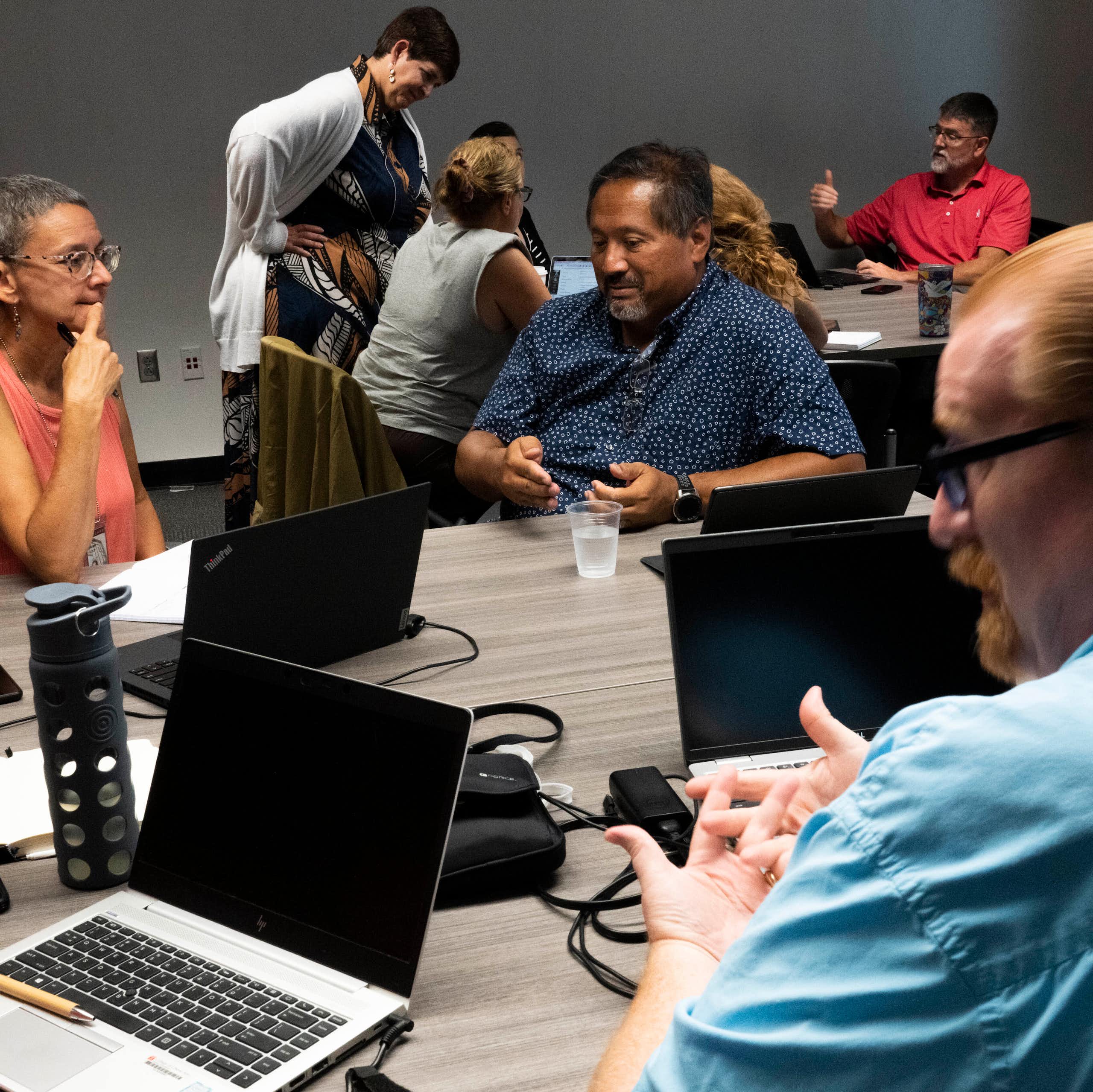 Group of teachers with laptops to discuss AI policies.