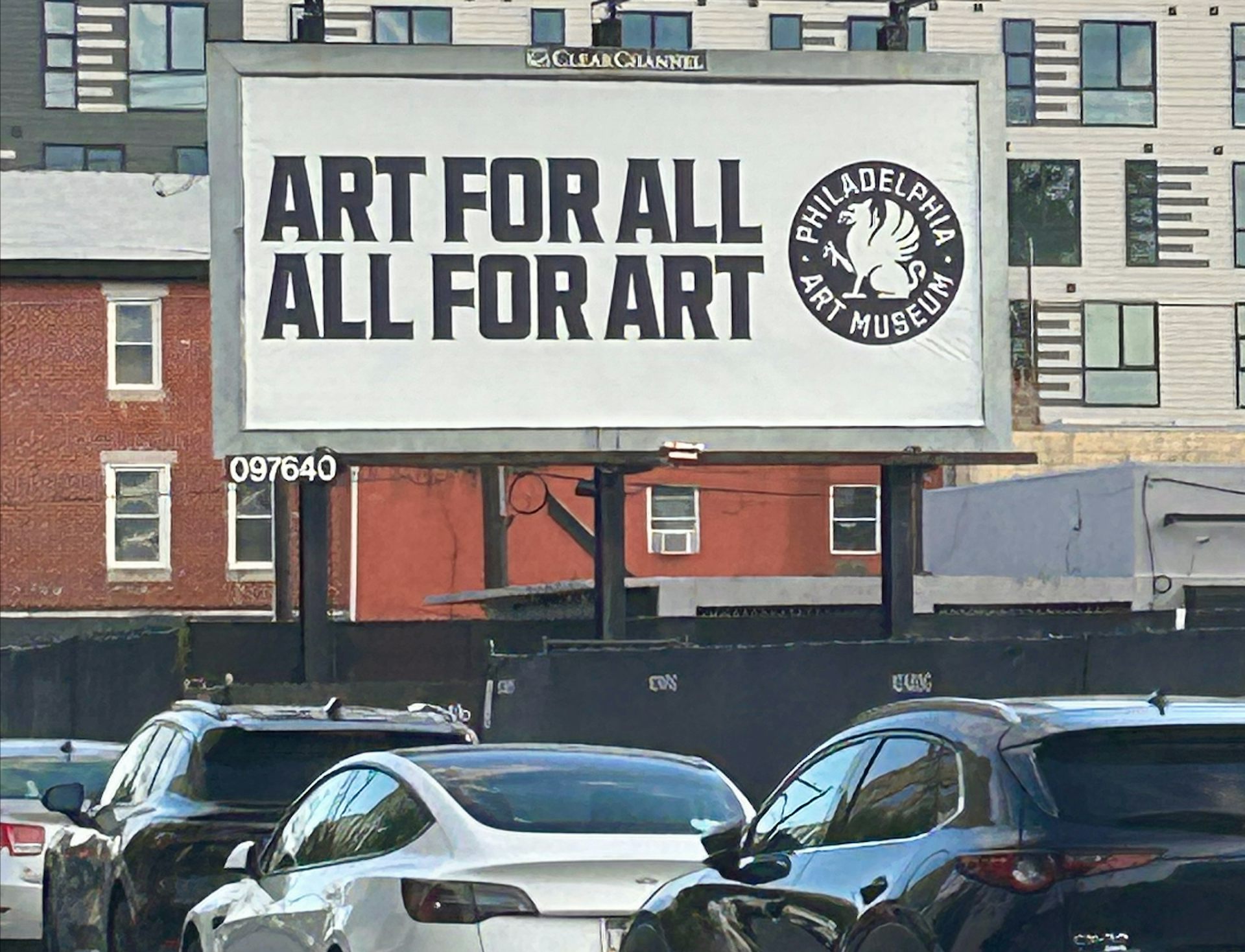 A billboard on urban street reads 'Art for all, All for art'