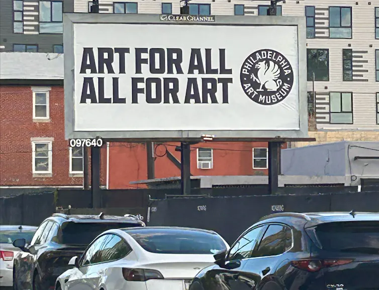 A billboard on urban street reads 'Art for all, All for art'