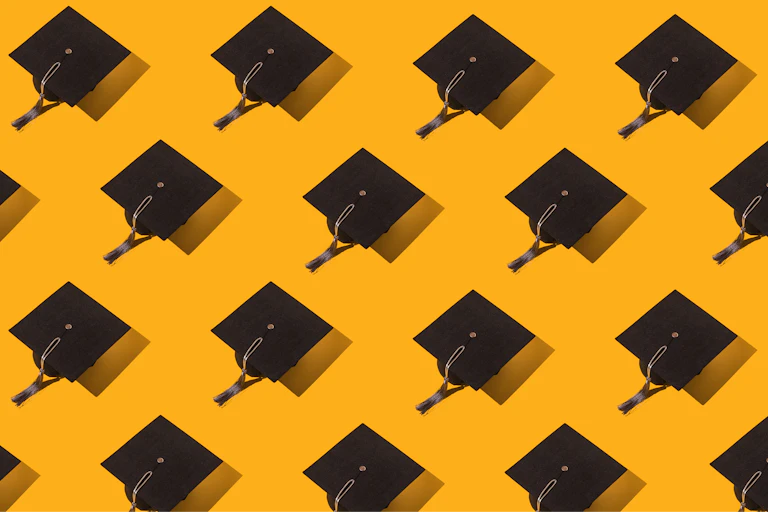 Black graduation caps are seen against a yellow background.