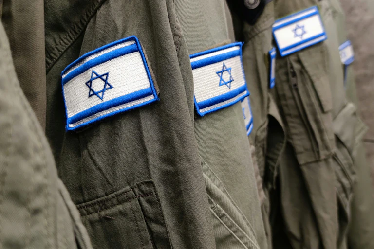 Four Israeli soldiers show their jackets emblazoned with the Israeli flag.