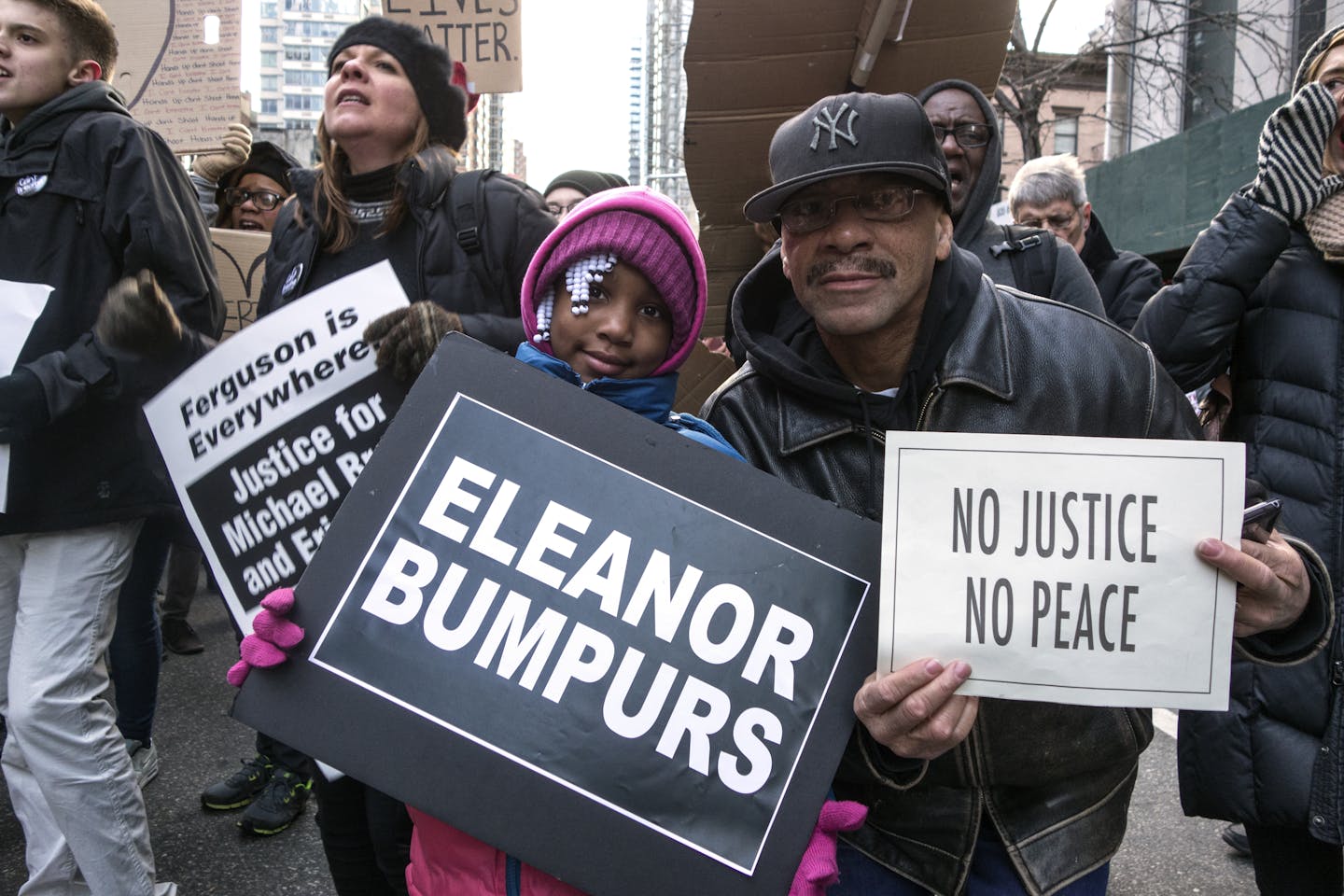Protesters hold signs reading 'Eleanor Bumpurs,' 'No Justice No Peace,' and 'Ferguson is Everywhere Justice for Michael Brown and Eric Garner'.