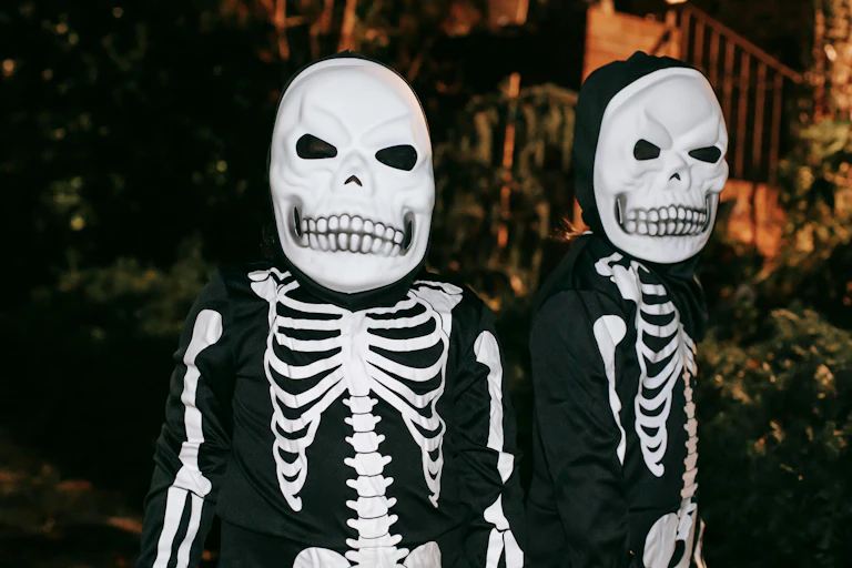 Two children in skeleton costumes and masks.