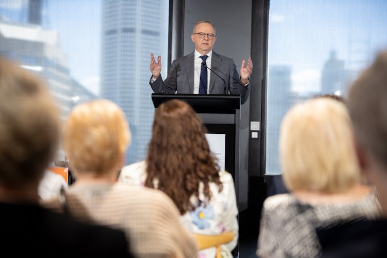 Anthony Albanese stands in front of a crowd at a lectern