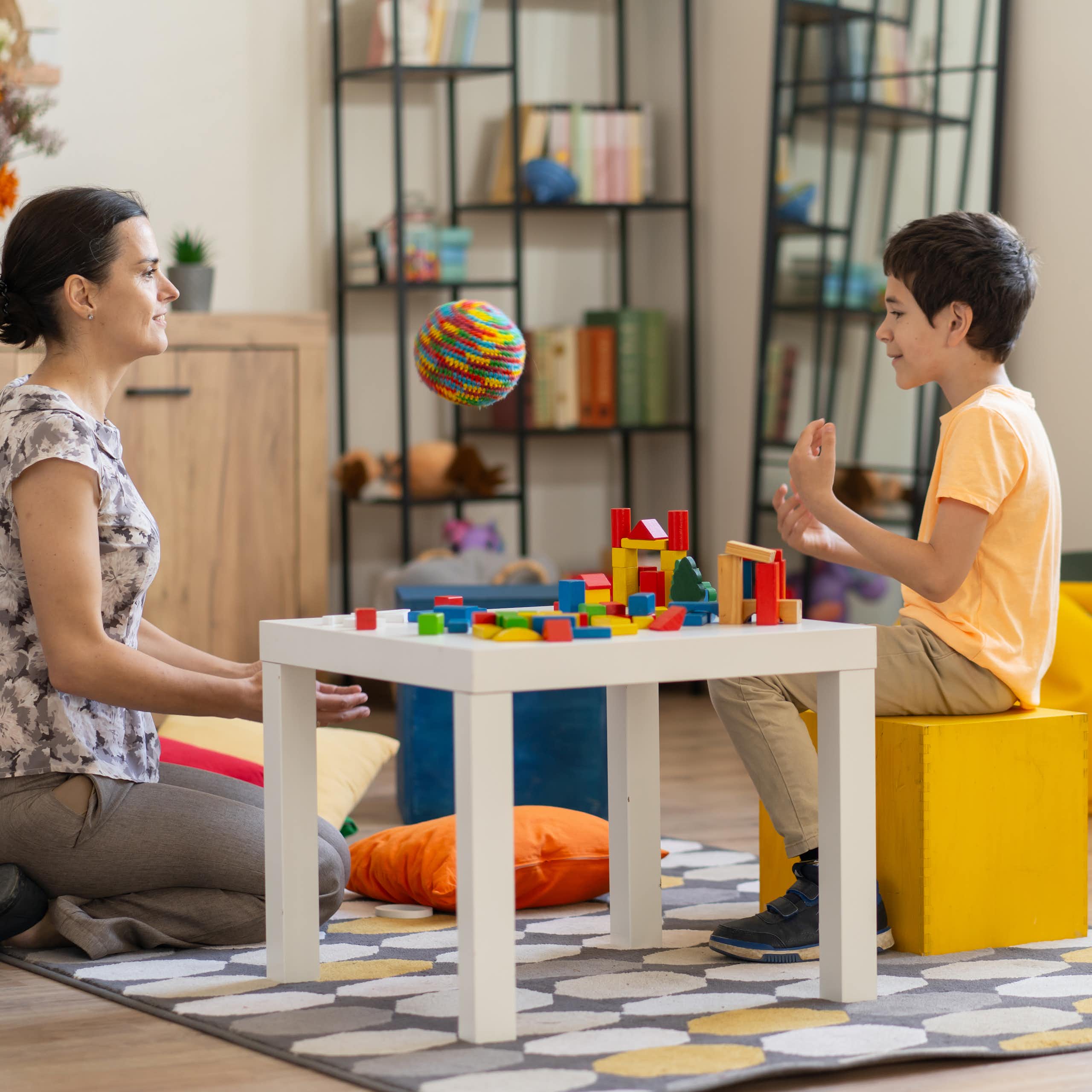 Boy with therapist at a table covered in colorful blocks