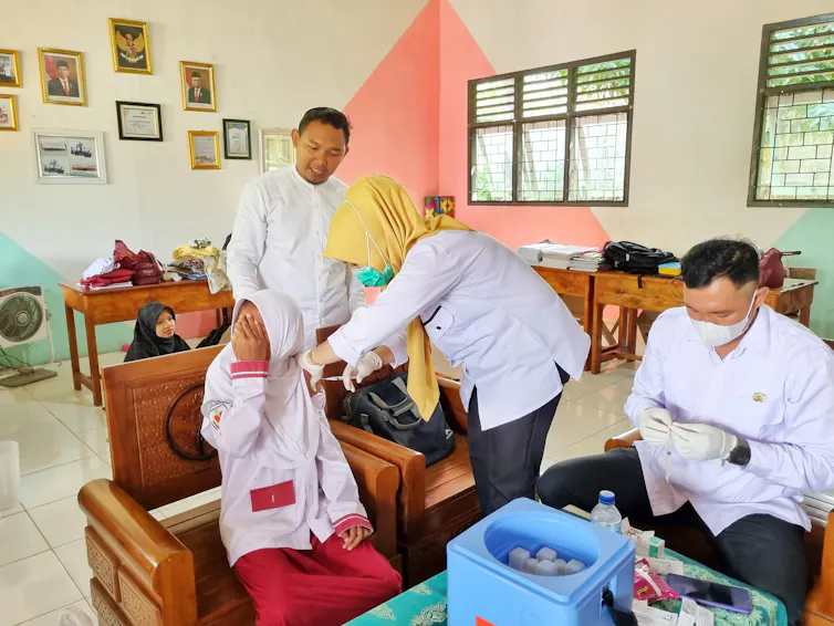 Bidan saat vaksinasi anak SD.