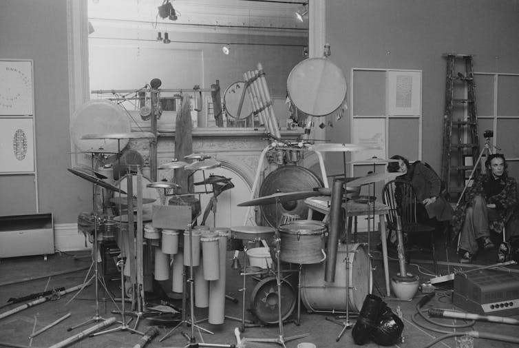 Eno in a recording studio with various drums and drum kit