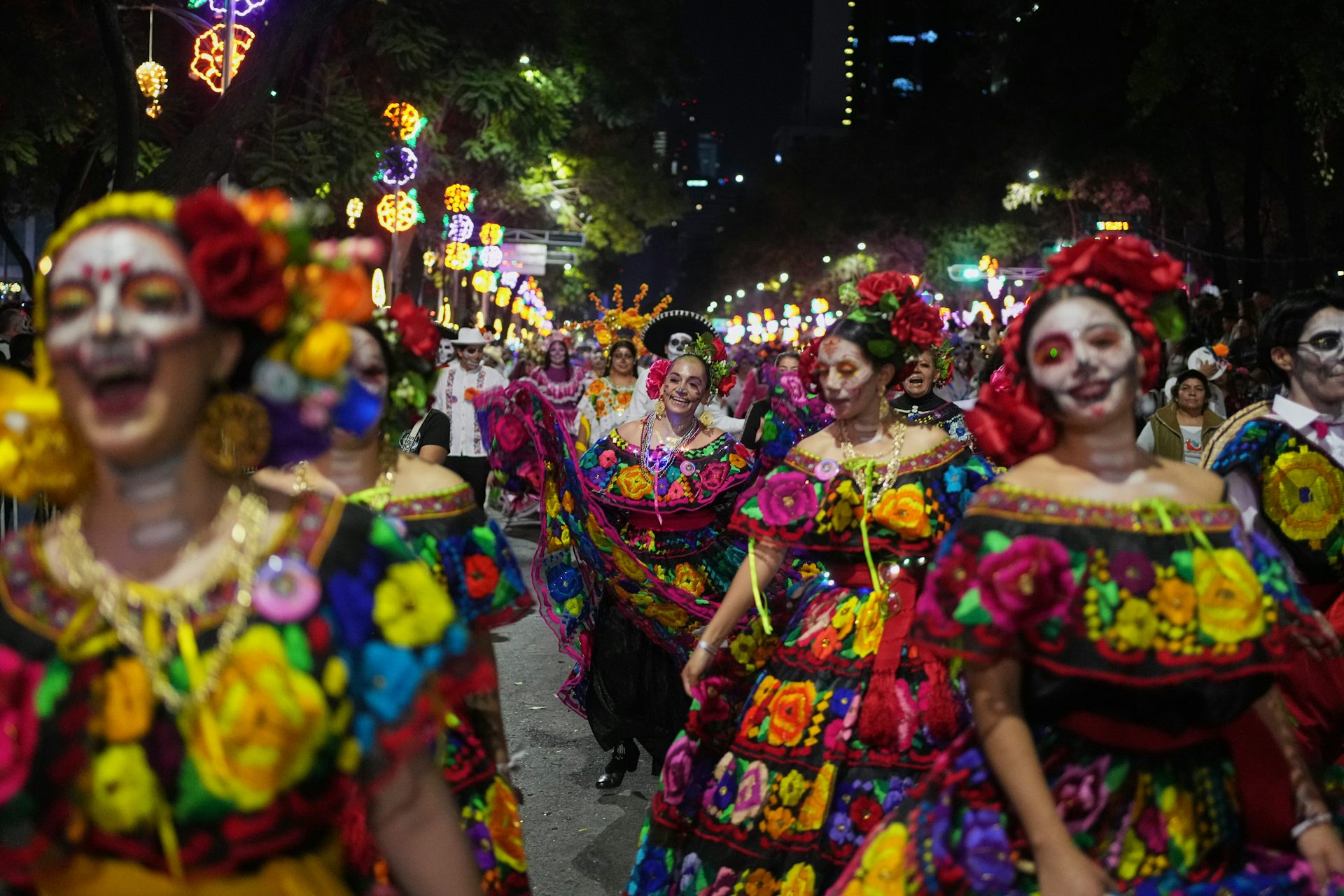 women in colorful dresses and make up walk in a parade