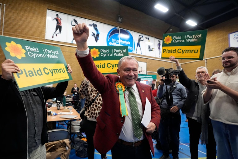 Lindsay Whittle standing at the centre with a hand in the air surrounded by his supporters