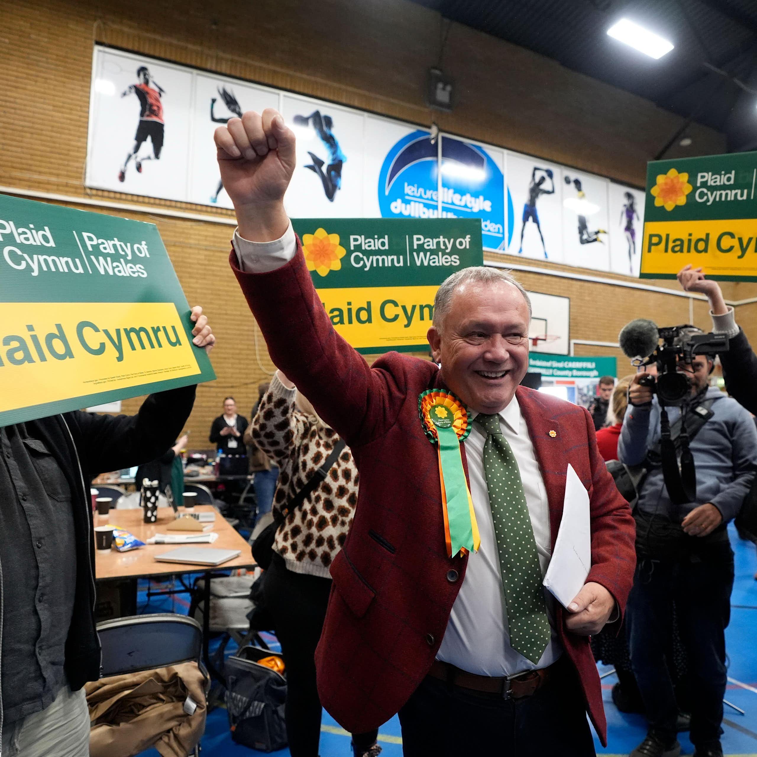Lindsay Whittle standing at the centre with a hand in the air surrounded by his supporters