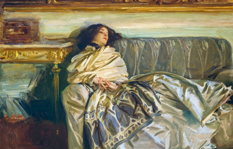 Woman sleeping on sofa wearing silk dress.