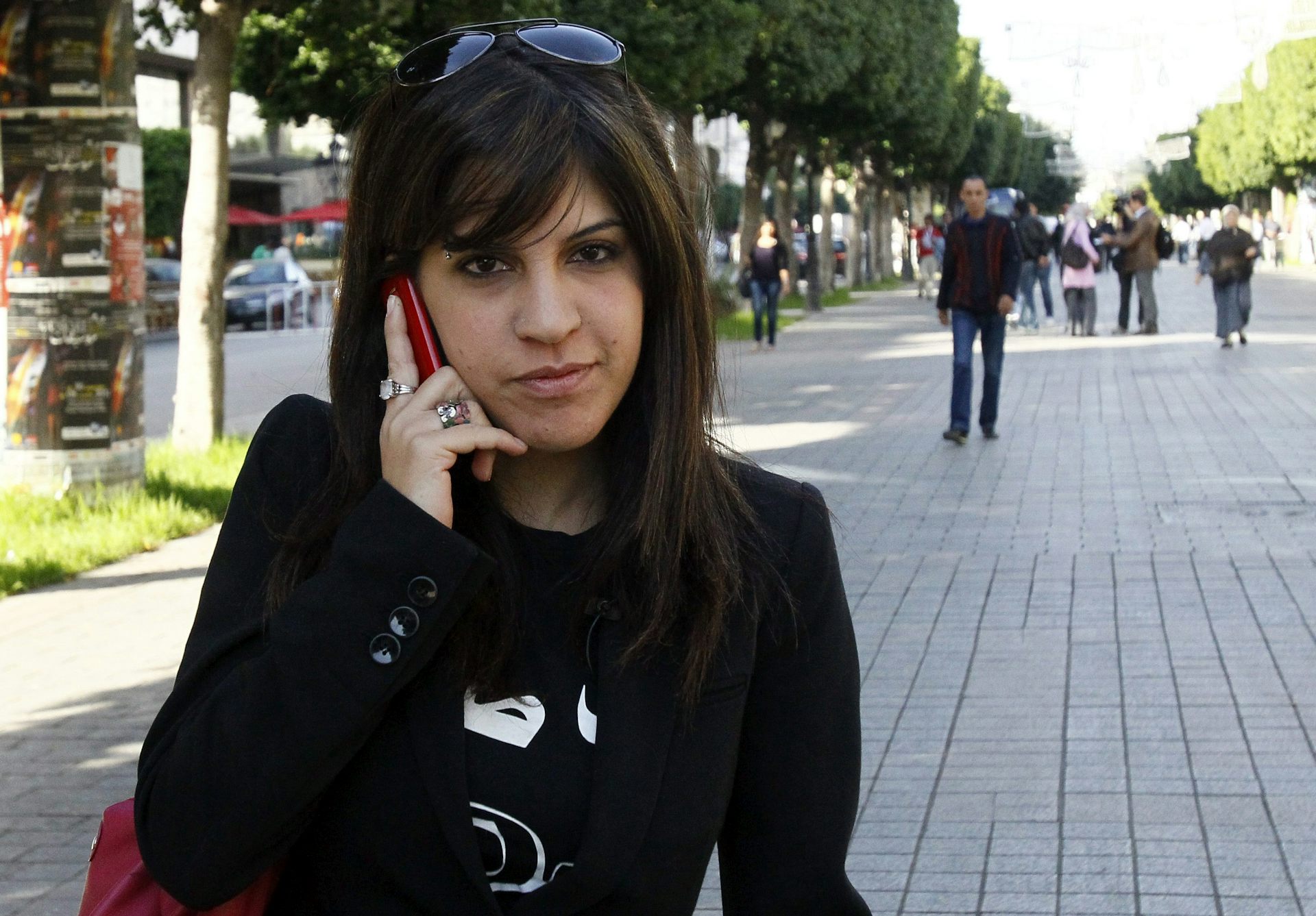 Una mujer en su teléfono sonríe a la cámara.