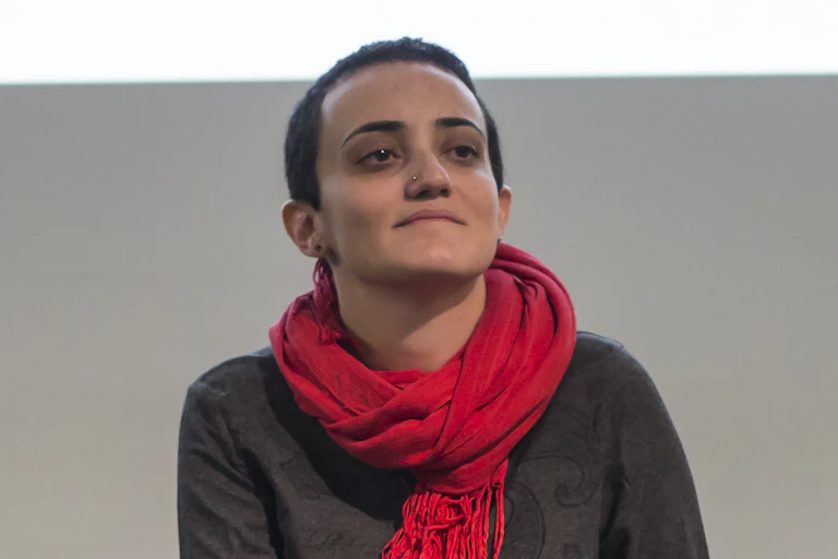 A woman with a red scarf smiles at the camera.