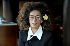 A woman with glasses answers questions at an interview.